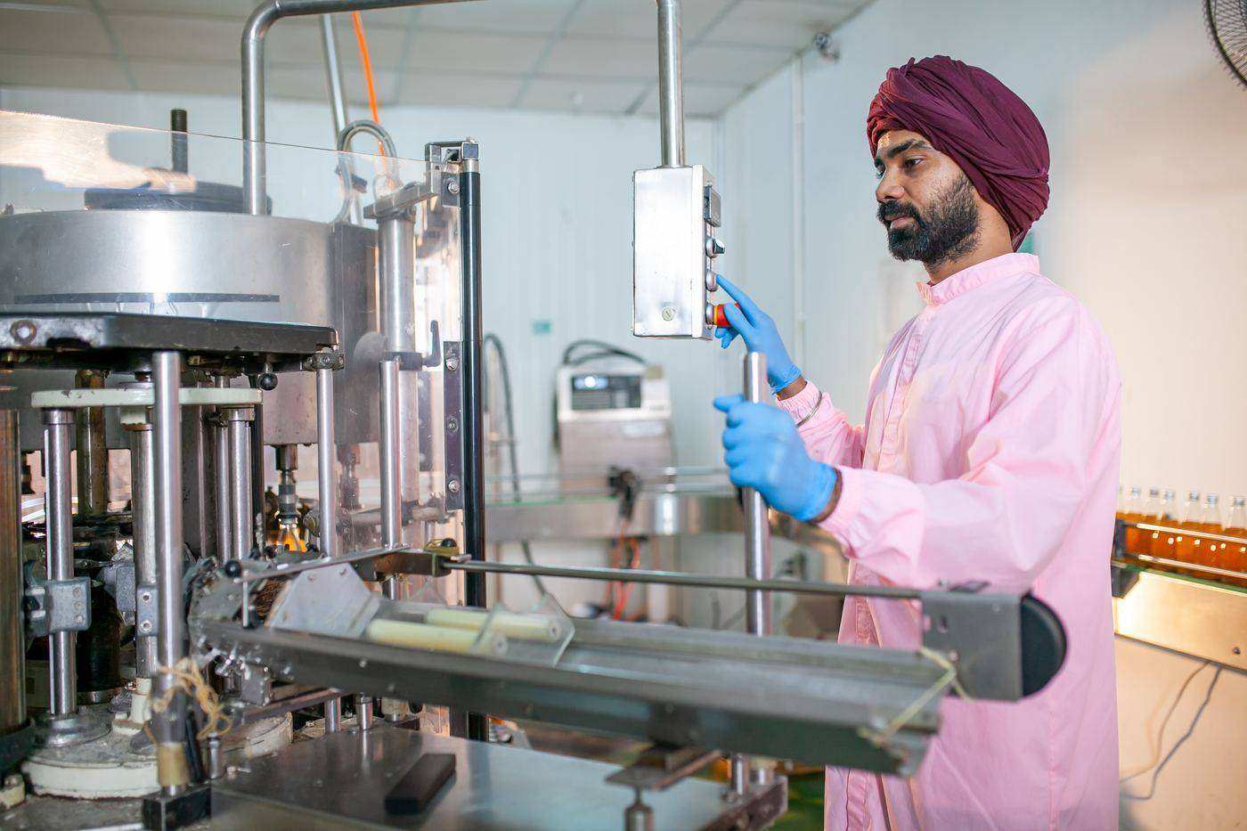 A line operator in a clean coat and gloves starting a filling machine on a packing line